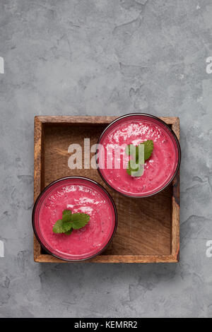 Bacca rossa frullati di frutta in vetri su un cemento grigio Sfondo. vista da sopra. spazio copia Foto Stock