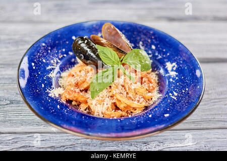 La pasta servita con cozze e basilico fresco. delcious pasta con frutti di mare e il parmigiano blu sulla piastra di porcellana. Foto Stock