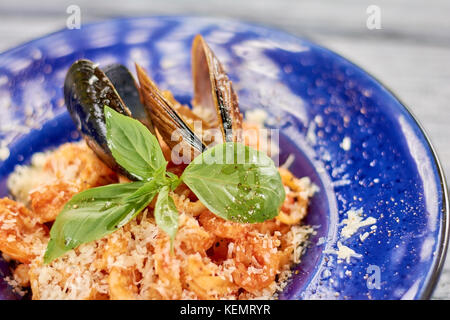 Gustosa la pasta con le cozze e basilico. deliziosa pasta frutti di maré close up di pasta con frutti di mare e salsa rossa. deliziosa cena sulla piastra. Foto Stock