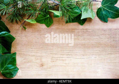 Confine da foglie d'edera e Abete rami astratti sfondo di legno. topw visualizzare e copiare lo spazio Foto Stock