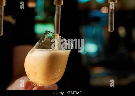 Barista versando birra fresca in pub. close up barman lato erogazione birra lager in vetro. Foto Stock