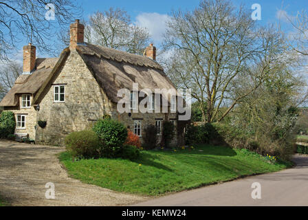 Casa indipendente, con camini e un tetto di paglia, alla periferia del villaggio di Harringworth, Northamptonshire, Regno Unito Foto Stock