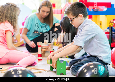 Pre-scuola boy cooperante con i ragazzi sotto la guida di kindergar Foto Stock