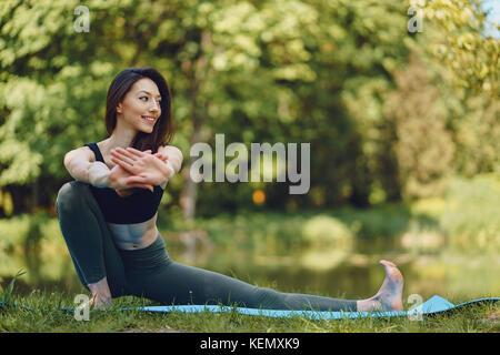 Bella e snella ragazza fare yoga nella natura Foto Stock