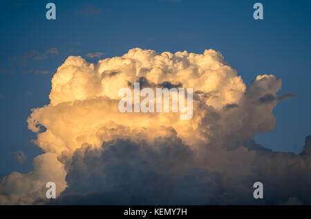 Una fotografia di drammatiche nubi accese dal sole su un cielo blu Foto Stock