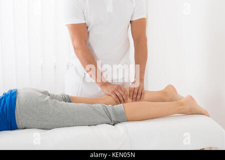 Close-up di uomo dando massaggio delle gambe di donna in spa Foto Stock