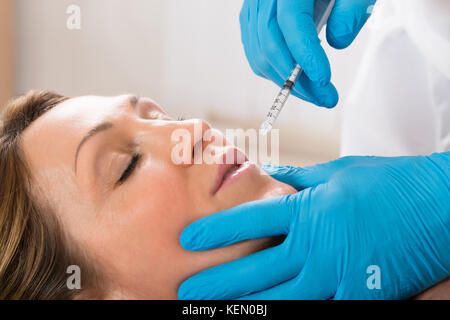 Donna matura cosmetico ricevente iniezione con siringa in clinica di bellezza Foto Stock