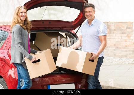 Coppia felice coppia di mettere la scatola di cartone nel baule auto Foto Stock