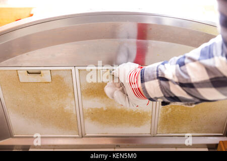 Repairman tenendo sudicia in maglia di alluminio filtro fuori della cappa Foto Stock