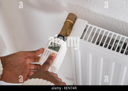 Close-up di una donna di mano la regolazione della temperatura sul termostato Foto Stock