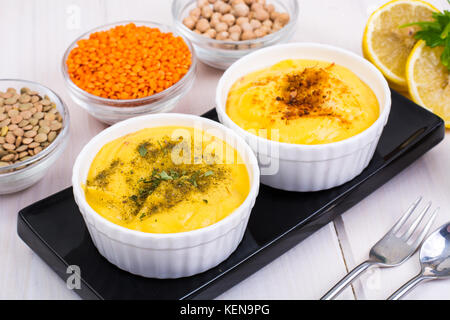 Due ciotole con fatti in casa hummus sul bianco sullo sfondo di legno. studio foto Foto Stock