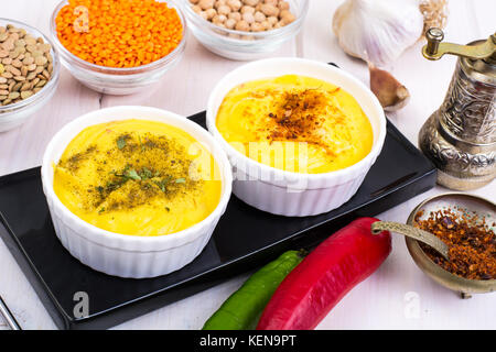 Due ciotole con fatti in casa hummus sul bianco sullo sfondo di legno. studio foto Foto Stock