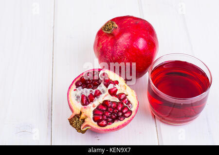 Il Melograno e succhi di frutta in vetro bianco su sfondo di legno. studio foto Foto Stock