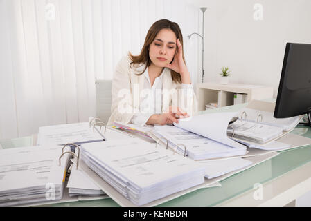 Stanco giovane ragioniere lavorano con documenti di office Foto Stock