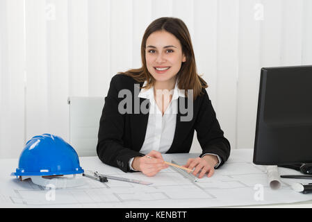 Giovani felici architetto femmina blueprint di disegno in ufficio Foto Stock