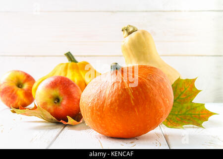 Zucca e Patty pan, mele e acero, rovere foglie gialle su una bianca tavolo in legno. raccolto autunnale. Foto Stock