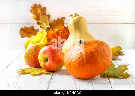 Zucca e Patty pan, mele e acero, rovere foglie gialle su una bianca tavolo in legno. raccolto autunnale. Foto Stock