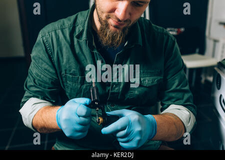 Tatuaggio artista master prepara gli strumenti per tatuaggio Foto Stock