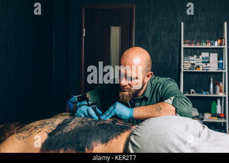 Tattoo studio tatuaggio artista al lavoro con la macchina per tatuaggio,  gli aghi pungono colore in pelle Foto stock - Alamy