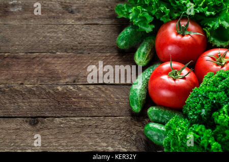 Pomodori freschi, cetrioli, insalata su sfondo di legno Foto Stock