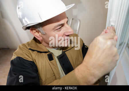 Operaio edile costruzione nuova casa e finestra di montaggio Foto Stock