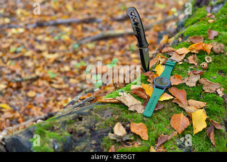 Set di maschi - coltelli e orologi. nero coltello e smart watch in autunno forrest Foto Stock