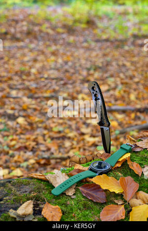 Set di maschi - coltelli e orologi. nero coltello e smart watch in autunno forrest Foto Stock