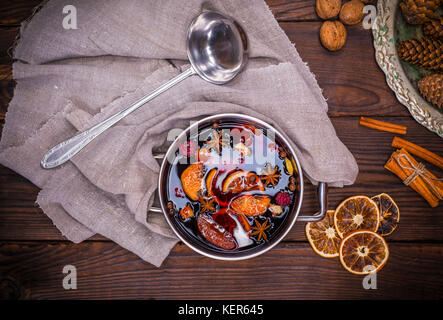 Vin brulé in una pentola con maniglie e gli ingredienti per la realizzazione di un fatto in casa bevanda alcolica su un di legno marrone, sfondo vista superiore Foto Stock