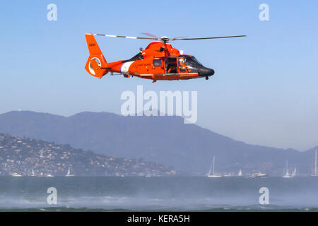 Coast Guard MH-65 Delfino elicottero dalla stazione aerea di San Francisco si libra sopra la baia di San Francisco. Foto Stock