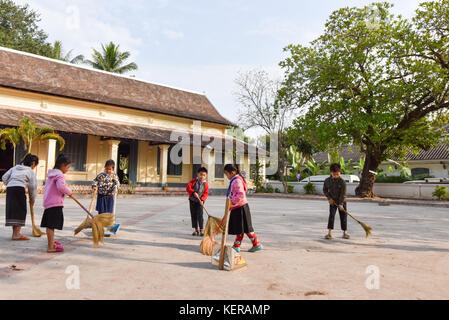 Gli scolari schoolyard pulizia al mattino Luang Prabang Laos Foto Stock