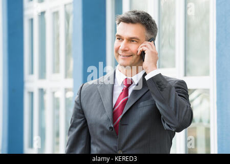 Coppia happy businessman parlando al cellulare al di fuori Foto Stock