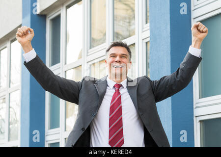 Maturo di successo imprenditore entusiasta alzando il pugno in aria Foto Stock