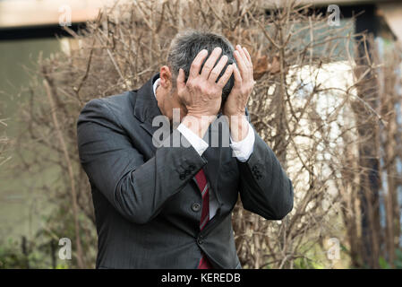 Imprenditore maturo in depressione con le mani sul fronte Foto Stock