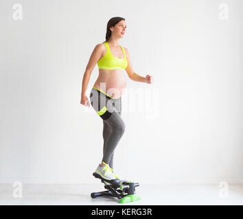 Una giovane donna incinta facendo esercizi di fitness presso lo studio Foto Stock