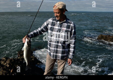 Sea bass fisherman con asta e cattura Foto Stock