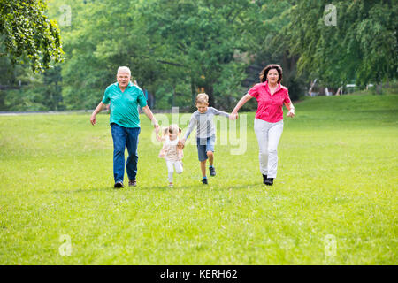 La famiglia felice divertirsi giocando nel parco Foto Stock