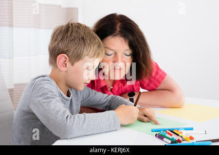 Babysitter disegno su carta con il ragazzo a casa Foto Stock