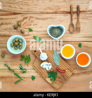 Diversi tipi di olio di cottura,l'olio d'oliva aromatizzato e olio di sesamo con erbe aromatiche spezie rosmarino ,il timo,l'aneto,salvia e menta prezzemolo e il cucchiaio di legno impostato Foto Stock