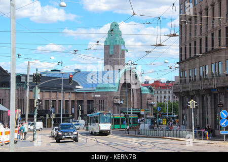 Vista diurna della città: La stazione ferroviaria principale con la torre dell'orologio e la strada con il complesso commerciale con tram e auto sullo sfondo blu Foto Stock