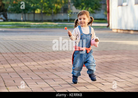 Funny bambina salti di gioia.Un giovane bambino in tuta in jeans Foto Stock