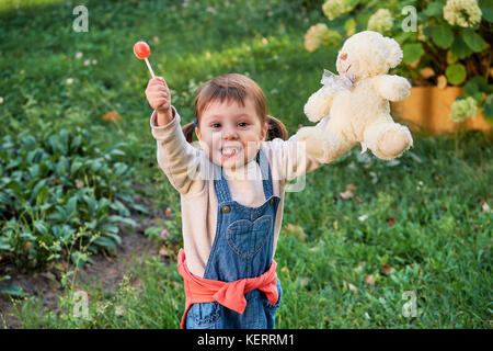 Funny bambina salti di gioia.Un giovane bambino in tuta in jeans Foto Stock