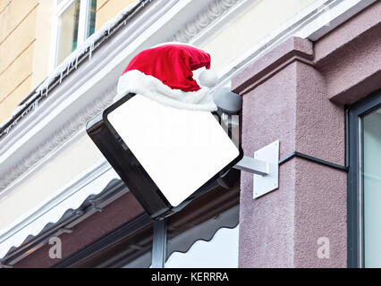 Vuoto bianco outdoor segnaletica aziendale mockup decorate con rosso di santa claus hat durante le vacanze di natale Foto Stock