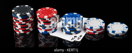 Chip e carte da poker si trovano in lunghezza su uno sfondo nero con la riflessione Foto Stock