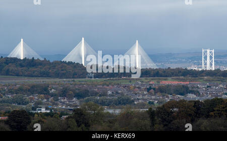 Una vista del nuovo Queensferry Crossing e Ponte di Forth Road illuminata dal sole con Kirkliston villaggio in primo piano su una noiosa giornata di ottobre. Foto Stock