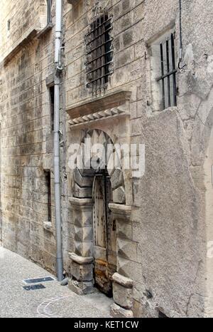 Pesante porta di legno e finestre sbarrate, di una vecchia prigione o con il carcere nel quartiere ebraico di pezenas, languedoc, Francia Foto Stock