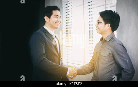 Asian business persone si stringono la mano e sorridendo il loro accordo per firmare il contratto e la finitura di una riunione Foto Stock