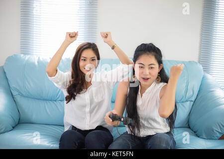 Due donne asiatiche competitiva amici per giocare con i videogiochi eccitato e felice allegro a casa Foto Stock
