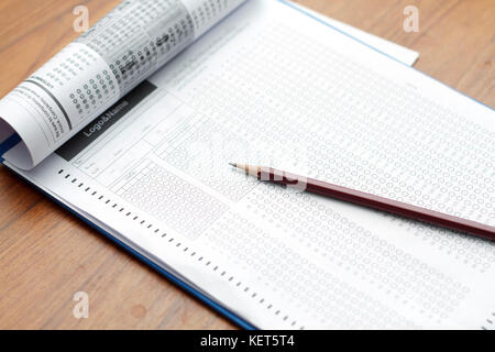Bicchieri e matita su standard sotto forma di test con risposte fatto gorgogliare in e una matita, focus sul foglio di risposta Foto Stock