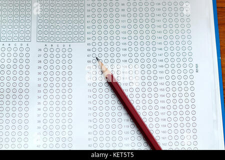 Bicchieri e matita su standard sotto forma di test con risposte fatto gorgogliare in e una matita, focus sul foglio di risposta Foto Stock