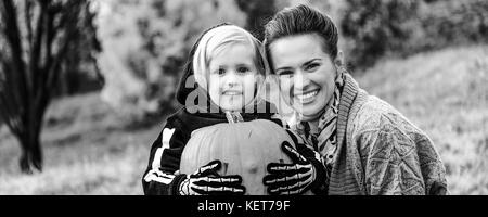 Dolcetto o scherzetto. Felice giovane madre e figlia al parco con scolpita la zucca di Halloween Foto Stock